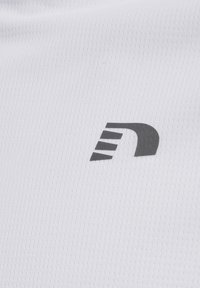 Weißer Sportstoff mit einer strukturierten Oberfläche, die ein markantes schwarzes Logo aufweist, das einem stilisierten Buchstaben "N" ähnelt.