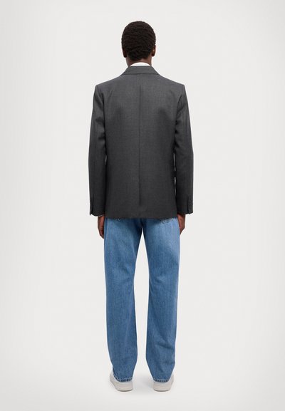 Grå blazer med en skræddersyet pasform, parret med løse lyseblå jeans. Blazeren har en notch-lapel og to bagventiler.
