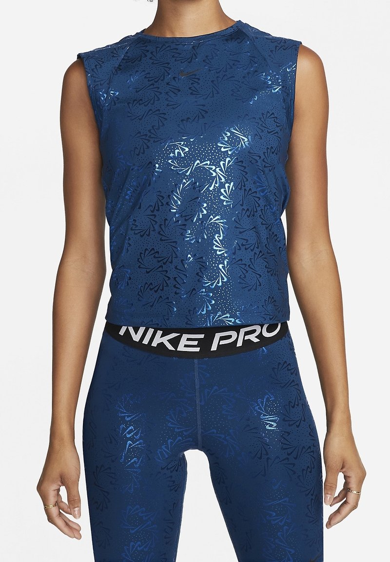 Top deportivo sin mangas azul marino con estampado floral, textura brillante, cuello redondo y logo de Nike; combinado con leggings ajustados a juego y cintura elástica.