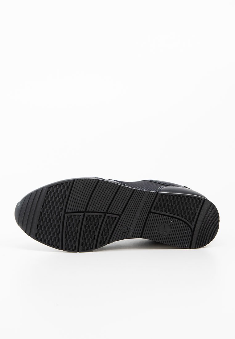 Schwarze Sportschuhsohle aus strukturiertem Gummi mit unterschiedlichen Mustern für besseren Halt. Glatte Kanten und leicht erhobene Bereiche sind sichtbar.