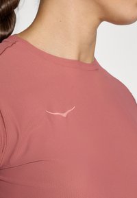 T-shirt de manga curta em rosa envelhecido. Tecido texturizado com decote redondo e detalhe discreto do logo no peito.