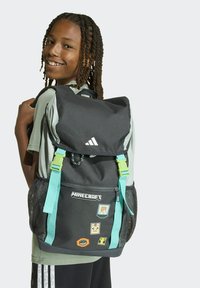 Čierny batoh so zelenými akcentmi, textúrovanou tkaninou, nastaviteľnými popruhmi a nášivkami s témou Minecraftu na prednom vrecku.