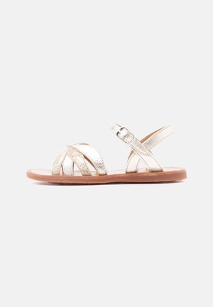 Platte sandaal met metallic gouden bandjes, een glinsterend voorbandje, verstelbare gesp en een bruine zool, zijaanzicht.