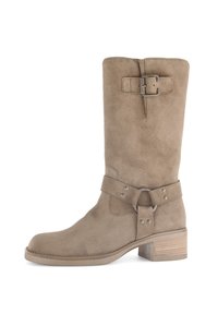 Bota de ante hasta la rodilla en marrón claro con punta redonda, una hebilla decorativa en la parte superior y una correa enrollada con acentos metálicos. Diseño de tacón cuadrado.