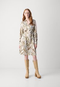 Rochie în stil înfoiat, cu un imprimeu floral, dintr-un material ușor, cu mâneci lungi, talie strânsă și tiv la nivelul genunchilor. Asortată cu cizme bej cu platformă înaltă.