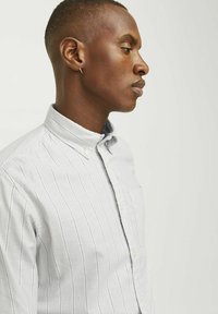 Jasnoszara koszula na guziki z pionowymi białymi paskami, z kołnierzykiem, pojedynczą kieszonką na piersi i strukturalnym materiałem.