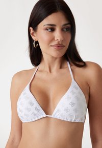 Biely bikiny top s trojuholníkovými pohárikmi, dekoratívnym strieborným potlačou, nastaviteľnými ramienkami a zhromaždeným švom na spodnej strane pre bezpečné nosenie.