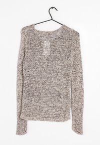 Kevyt, löysästi neulottu beige villapaita, jossa on pitkät hihat, pyöreä pääntie ja teksturoitu kuvio, riippumassa mustassa koukussa valkoista taustaa vasten.