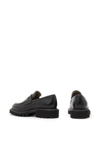 Chaussures noires en cuir à enfiler avec un profil bas, un bout rond et une semelle épaisse et texturée. Présentent des coutures discrètes et un design élégant.