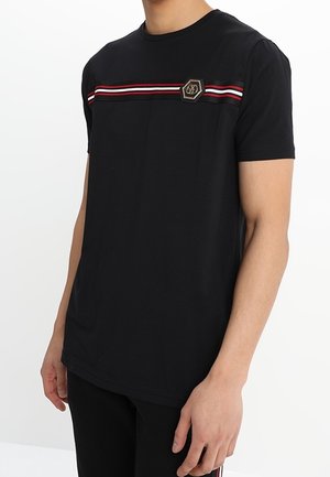 Czarna bawełniana koszulka z okrągłym dekoltem, z czerwono-białym paskowanym wzorem na klatce piersiowej i sześciokątnym logo jako akcentem.