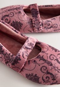 Pink velvet slippers with a decorative dark floral pattern, rounded toe, and a secure strap across the instep for added support.