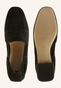 Mocassins en daim noir à bouts carrés, l’un montre la vue de dessus, l’autre la semelle beige avec le nom de la marque et la pointure 4,5.