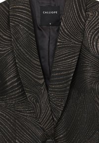 Blazer nero con un motivo a onde testurizzato in fili metallici dorati. Presenta un colletto a scapin e un'etichetta che dice "CALLIOPE", taglia S.