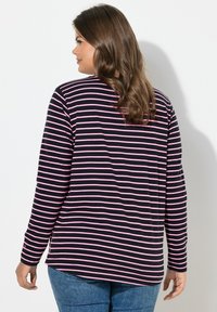 Černá košile s dlouhým rukávem a vodorovnými růžovými pruhy. Měkká látka, kulatý výstřih a mírně zaoblený spodní lem. Zobrazená zezadu.