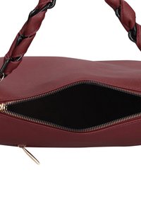 Borsa rossa in ecopelle con manico nero intrecciato. Dettagli con cerniera lungo l'apertura che mostrano l'interno nero. Texture liscia.