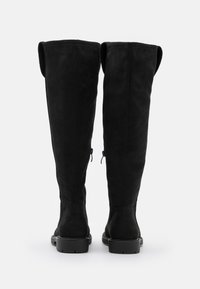 Botas negras hasta la rodilla hechas de suave ante, con punta redonda, suela plana y cremalleras laterales para facilitar su uso.