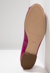 Semelle d'une chaussure en cuir rose avec un talon carré marron, une semelle beige lisse et un marquage "högl" près de l'arche.