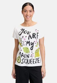 Biała bawełniana koszulka z czarnym napisem "Jesteś moim głównym skarbem!" z zielonymi ilustracjami cytryn i różowymi akcentami.