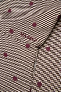 Mønstrede stoffer i houndstooth-design med maroon prikker. "MAX&Co" logo broderet. Farveskemaet inkluderer beige og mørkebrun.