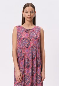 Sukienka bez rękawów w kwiatowy wzór w odcieniach różu i fioletu, z okrągłym dekoltem i wiązaniem z przodu oraz luźnym krojem.
