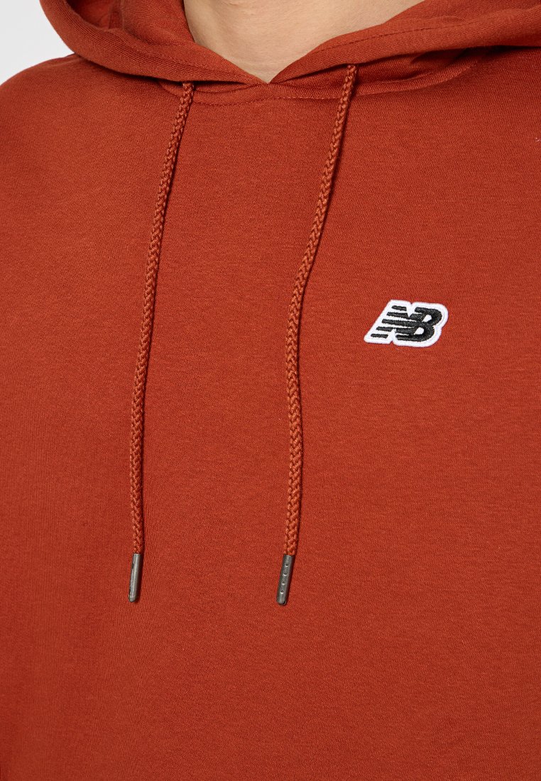 Bordowy bawełniany hoodie z regulowanym sznurkiem z metalowymi końcówkami oraz małym białym haftowanym logo na piersi. Gładka struktura.