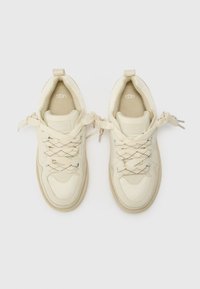 Beige sneakers met een gestructureerde mesh bovenkant, gevoerde kraag en patroonveters. UGG-logo op de tong en gevoerde binnenzool.