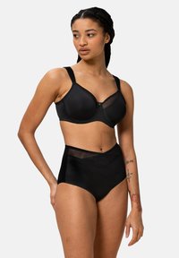 Musta alusvaatesetti, joka sisältää muotoiltuja rintaliivejä sileästä kankaasta ja korkeavyötäröiset alushousut, joissa on verkkoaccentteja ja saumatonta muotoilua.