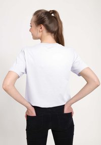 Hvid bomuld t-shirt med korte ærmer, rund halsudskæring og en afslappet pasform, parret med sorte denim jeans med bagside lommer.
