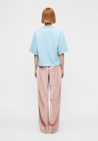 Ανοιχτό γαλάζιο τοπ με κοντά μανίκια, άνετη εφαρμογή. Μαλακό ροζ, ψηλόμεσο, φαρδύ παντελόνι από βελουτέ υλικό με λεπτομέρειες στο πλάι.