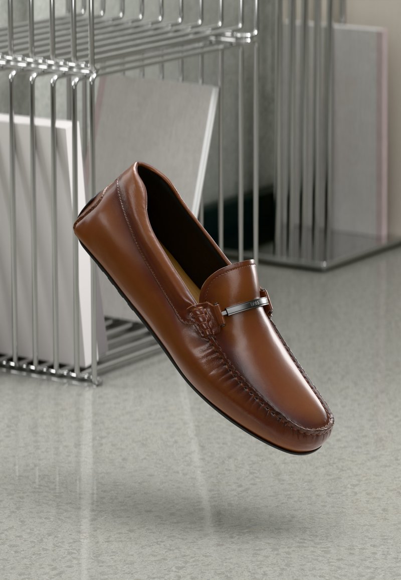 Loafers din piele maro cu cusături decorative, o textură netedă și un accent argintiu pe partea superioară. Ușori și fără șnururi.