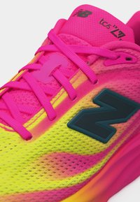 Lähikuva kirkkaan vaaleanpunaisesta ja keltaisesta New Balancen juoksukengästä, jossa on vaaleanpunaiset nauhat ja musta "N"-logo sivulla.