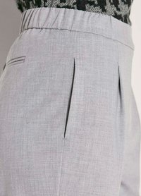 Lichtgrijze, op maat gemaakte broek met een gestructureerde stof, voorzien van voorplooien en zijzakken. Elastische tailleband voor comfort.