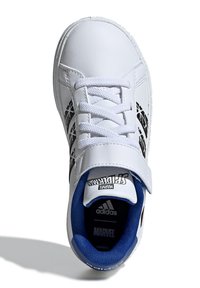 Baskets blanches avec un design Spider-Man noir et argent, intérieur bleu et lacets blancs. Comprend une sangle Velcro et une semelle en caoutchouc.