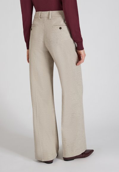 Licht beige wijde broek van geweven stof met twee achterzakken en bruine knopen, gecombineerd met een bordeauxrood langemouwen top.