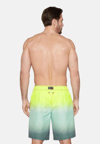 Înotări de culoare galben-verde strălucitor cu un design stilizat. Prezintă un brâu elastic și detalii cu logo.