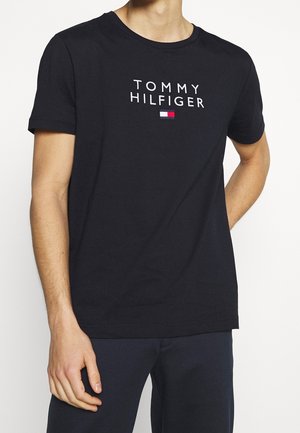 Granatowa bawełniana koszulka z krótkim rękawem, z logo "TOMMY HILFIGER" w kolorze białym oraz małym czerwono-niebieskim emblematem na piersi.
