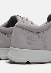 Baskets Timberland en daim gris avec logo arbre en relief, col rembourré, semelle blanche texturée et design à lacets, vues du côté du talon.