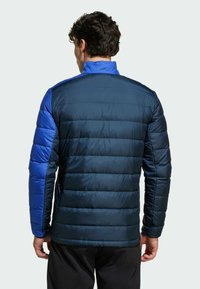 Vadderad jacka i mörkblått och marinblått, med hög krage, varierande paneltexturer och en slim fit med horisontella sömmar.