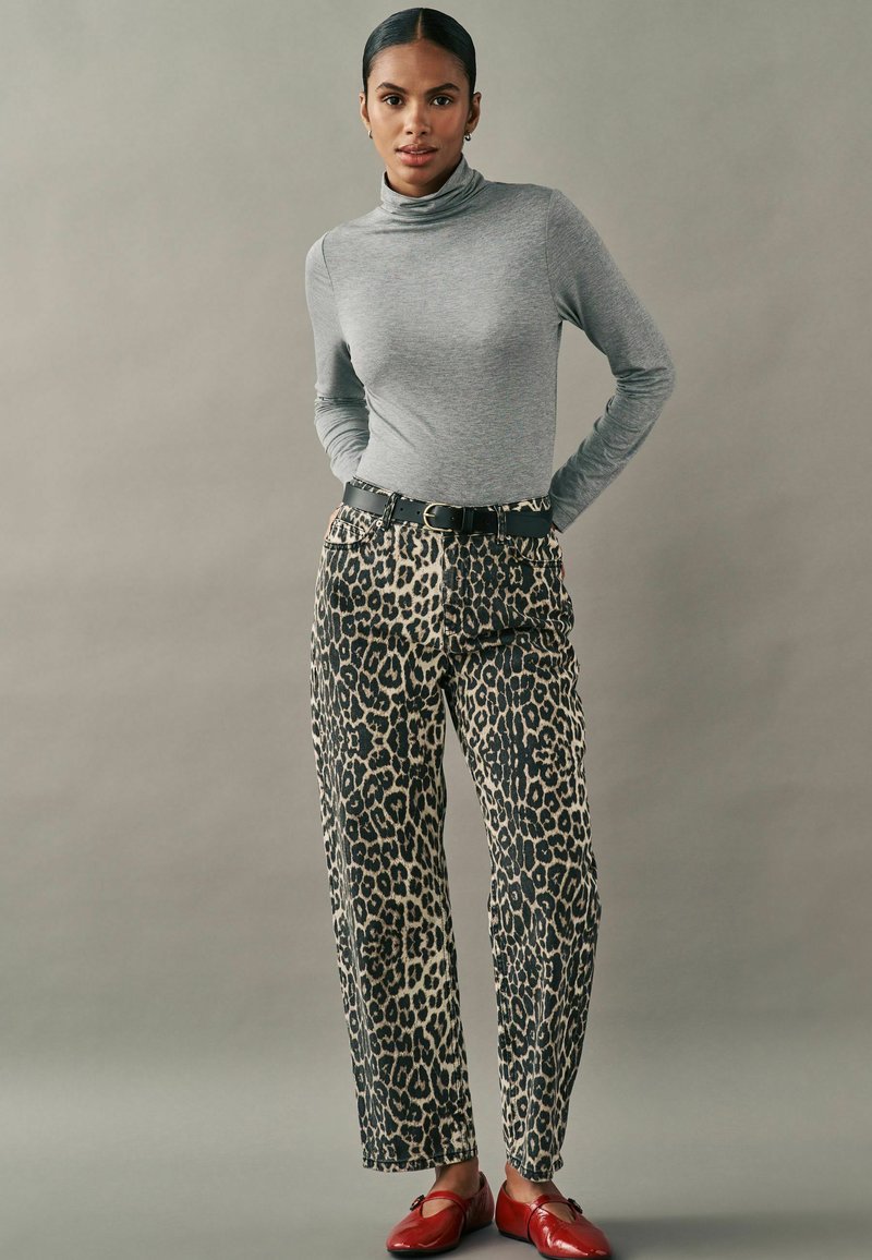 Grauer langärmeliger Rollkragenpullover kombiniert mit beigen und schwarzen Leopardenmuster-Hosen, akzentuiert durch einen schwarzen Gürtel und rote Ballerinas.