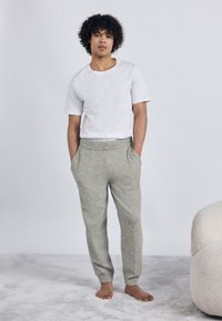 Ανοιχτό γκρι, φλις joggers με ελαστική ζώνη στη μέση και πλαϊνές τσέπες, σε συνδυασμό με ένα απλό λευκό κοντομάνικο μπλουζάκι. Χαλαρή εφαρμογή.