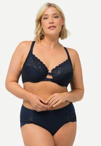 Reggiseno in pizzo blu navy con bordi scallop, supporto con ferretto e slip coordinato con dettagli in pizzo e un fiocco centrale.