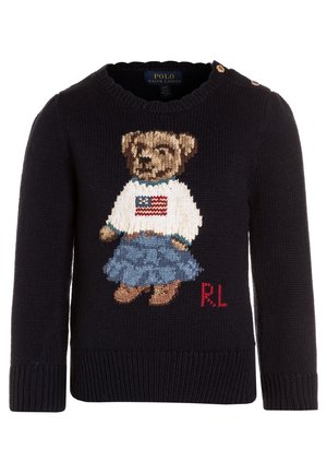 Maglione a maglia blu navy con grafica di un orso in camicia bianca con una bandiera americana, gonna di denim e scarpe marroni; include bottoni sulle spalle.