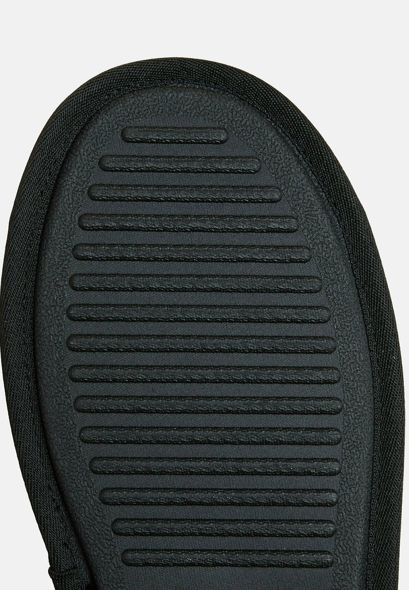 Suela de zapato de goma negra con surcos texturizados para mayor agarre, rodeada por un borde de tela negra. Forma ovalada y plana con un acabado suave.