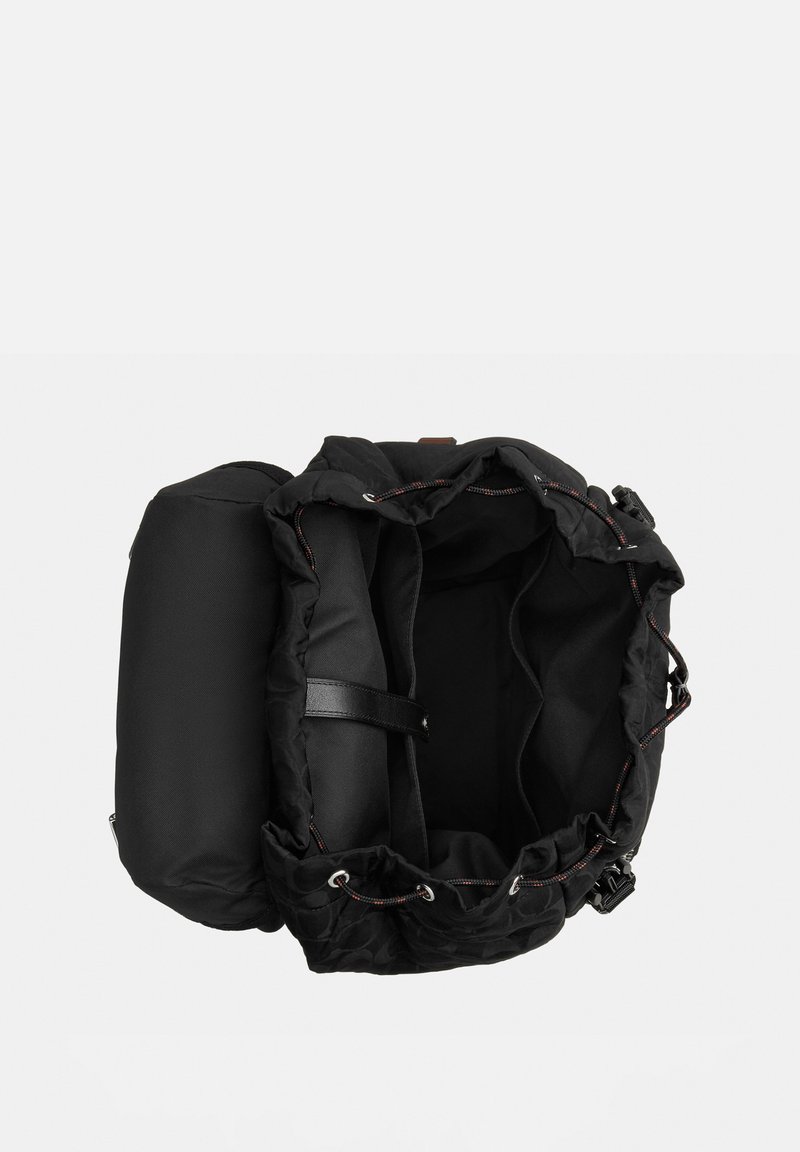 Black drawstring backpack open to show empty main compartment with internal divider and front pocket against white background.