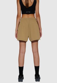 Bruine sportshorts met een elastische tailleband, met een losse pasvorm. Zwarte sokken en sportieve schoenen maken de outfit compleet.