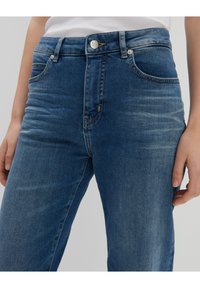 High-waisted blue jeans with a smooth denim texture, featuring five pockets, a zipper fly, and subtle fading along the legs.