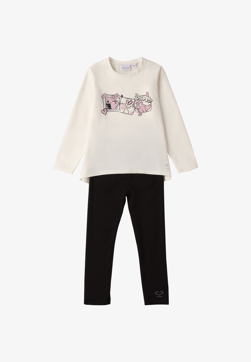 Crème langemouwen top met roze kat en "Oops!" graphics, gecombineerd met eenvoudige zwarte leggings met een klein hartdetail bij de zoom.