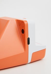 Orange device with a geometric design, featuring a power button and a USB-C port. Textured surface, complemented by white accents.