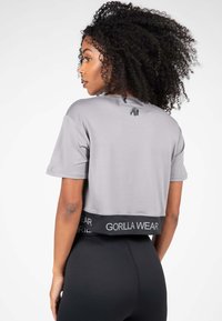 Grijze cropped t-shirt met korte mouwen, voorzien van een zwarte tailleband met de opdruk "GORILLA WEAR" en een kleine grafische afbeelding op de rug.