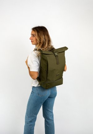 Zaino verde oliva con design a roll-top, tracolla regolabile e tasche laterali. Realizzato in tessuto durevole con una superficie liscia.